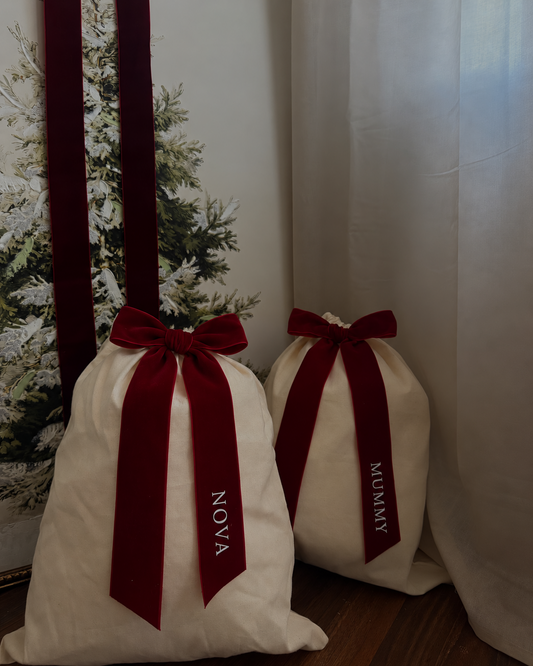 Personalised Christmas gift sacks beside a Christmas tree