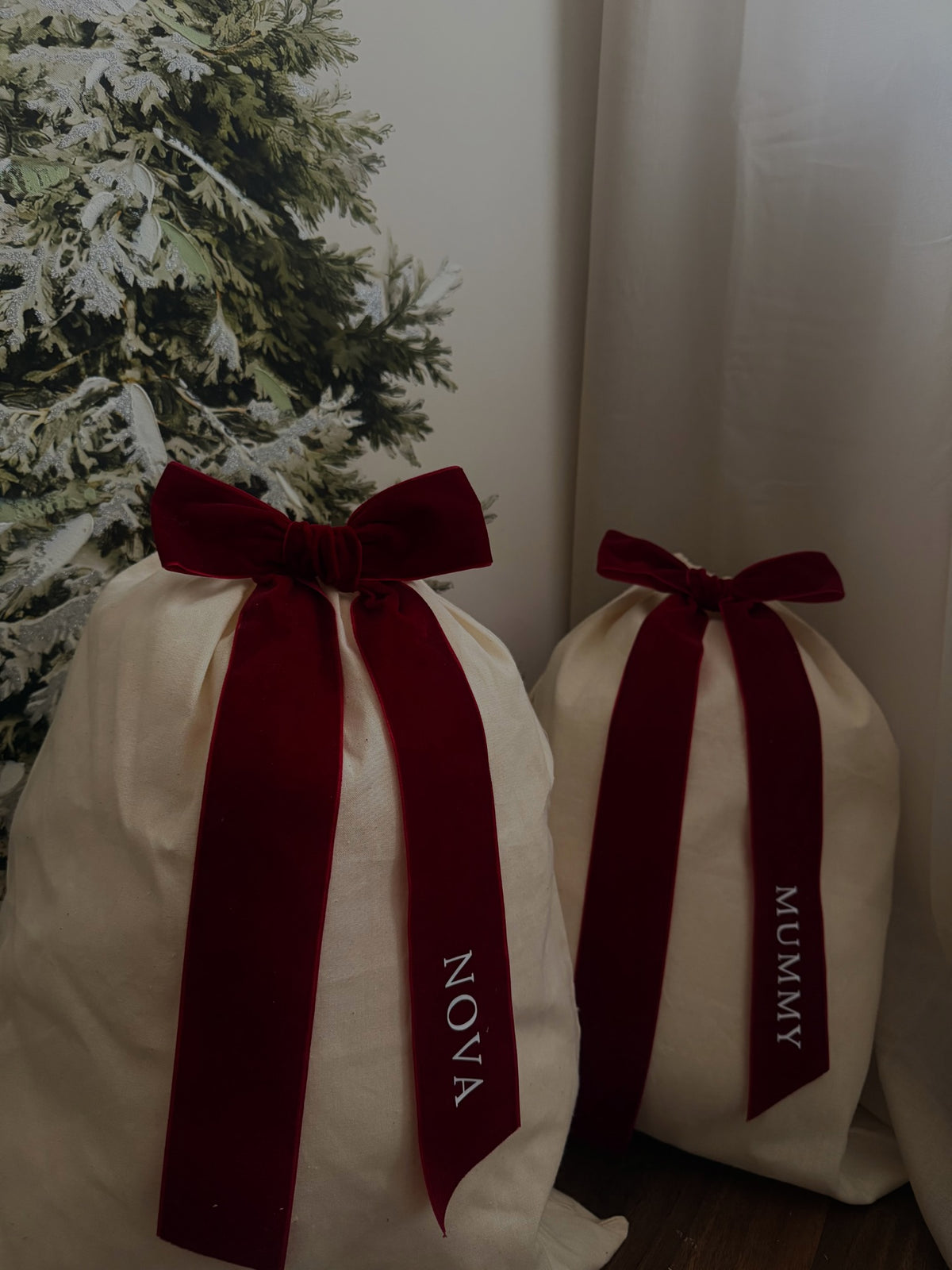 Natural-coloured Christmas gift sacks with burgundy bows personalised with Nova and Mummy